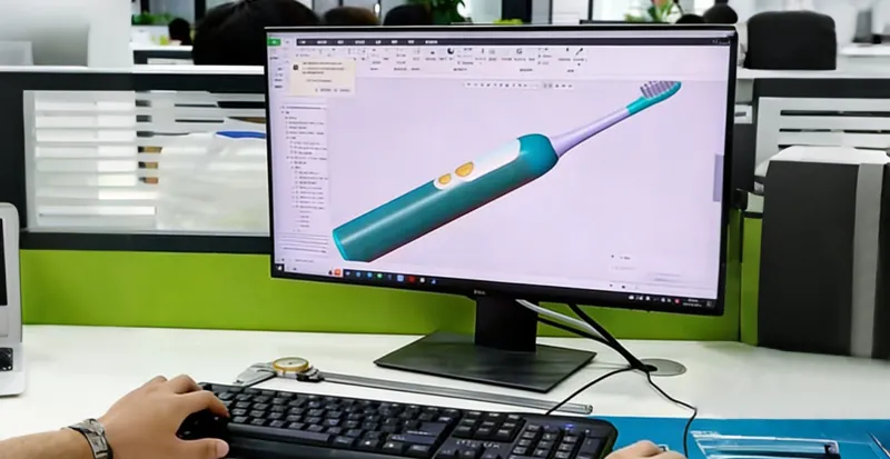 About 4 An R&D engineer working on 3D CAD modeling for a new electric toothbrush design on a computer monitor.