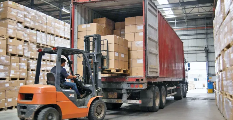 About 6 Forklift loading a shipping container with stock boxes of oral care products for swift global dispatch.