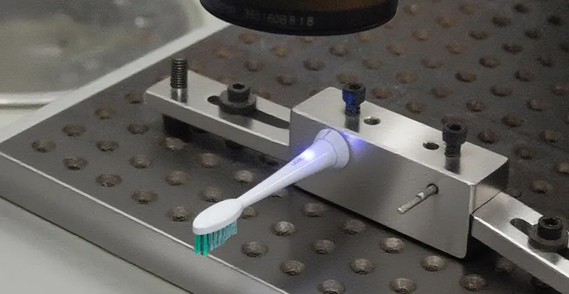About 5 Precision laser marking machine applying a custom brand logo onto a ready-to-brand electric toothbrush for turnkey private labeling.